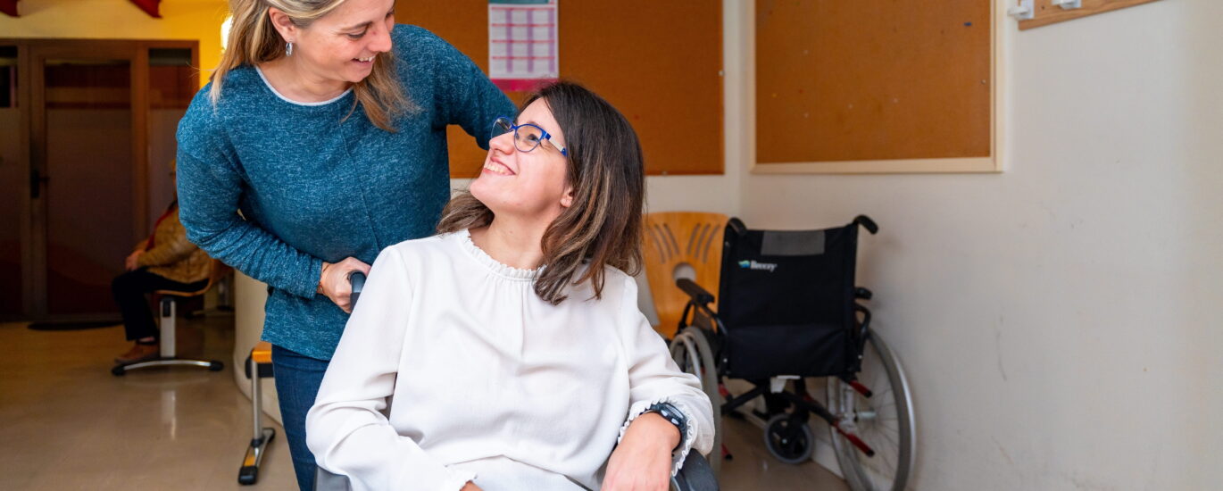 Caregiver helping woman in wheel chair with special needs.