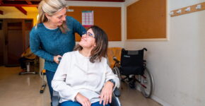 Caregiver helping woman in wheel chair with special needs.