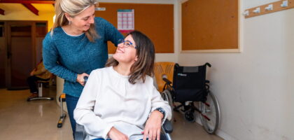 Caregiver helping woman in wheel chair with special needs.