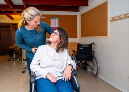 Caregiver helping woman in wheel chair with special needs.