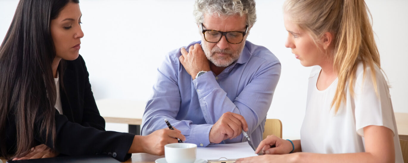 Family legal advisor explaining document details to mature father and adult child.