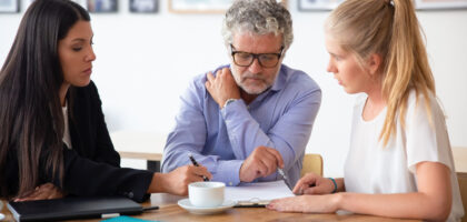 Family legal advisor explaining document details to mature father and adult child.