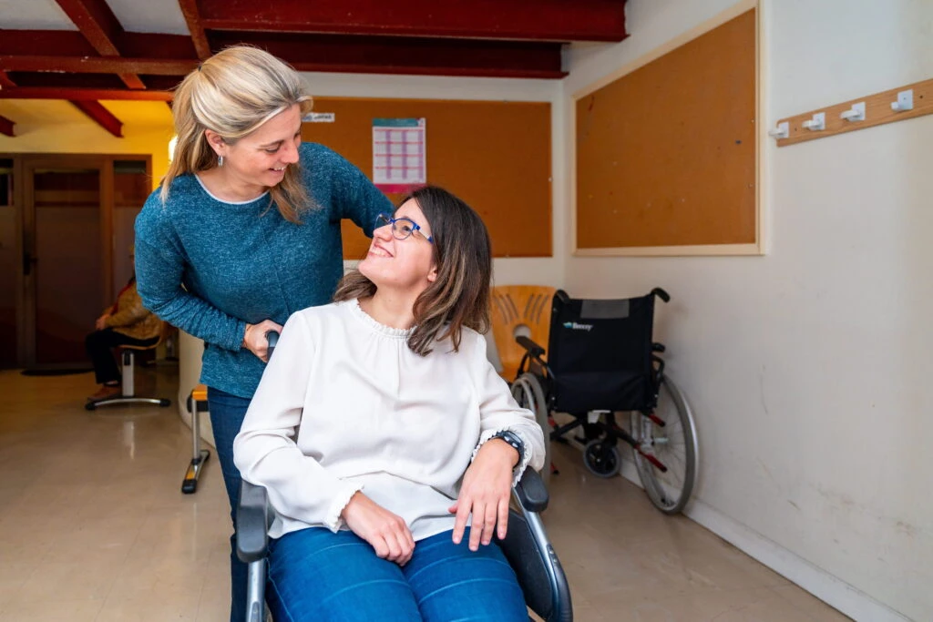 Caregiver helping woman in wheel chair with special needs.