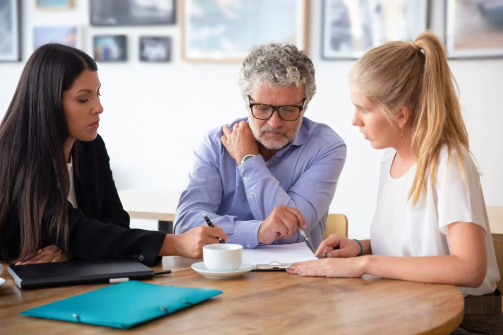 Family legal advisor explaining document details to mature father and adult child.