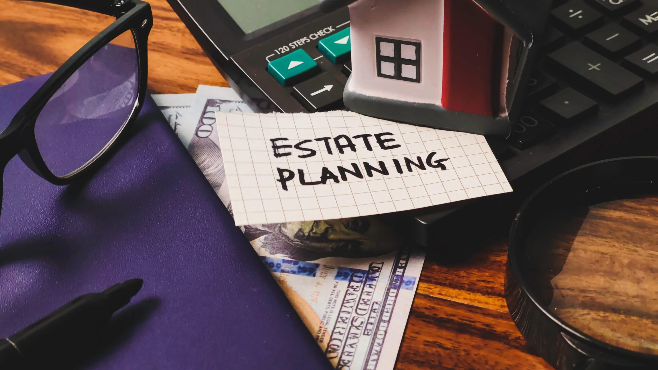 Estate Planning spelled out on graphing paper next to money, home and calculator. 